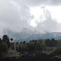 Mount Etna poking through the clouds, lava fields in front!