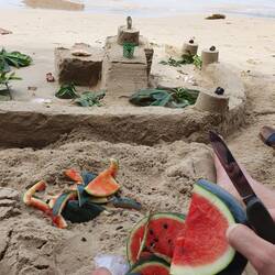 Sandburg bauen und Melone essen am Stand