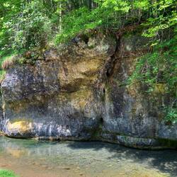 An der Felswand funkelten viele Lichtreflexe, die durch das Wasser entstanden sind