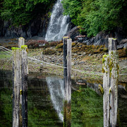 Waterfall and reflection ... with the pilings of the old pier — Orca Lodge ... Cordova, AK.