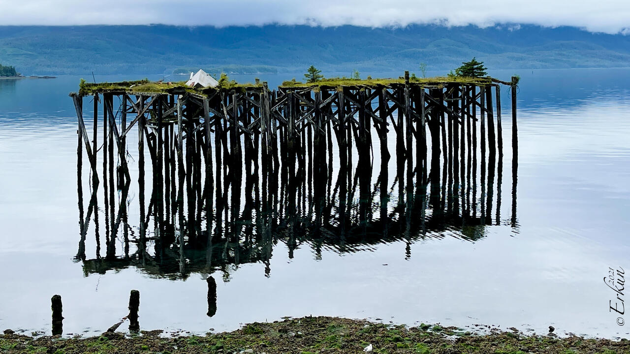 This old pier, reflected on Orca Inlet, feels like it's floating in the air — Orca Lodge ... Cordova