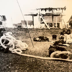 Historic photo showing a woman inflating walrus intestine for a waterproof garment.