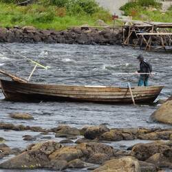 In dem Boot steht der Fischer und arbeitet mit dem Kescher.
