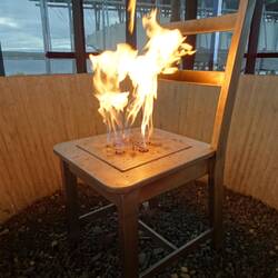 Im sogenannten Pavillon symbolisiert dieser permanent brennende Stuhl den Scheiterhaufen.