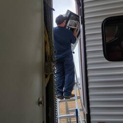 RV service technician replacing the rooftop a/c