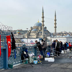 Galata Bridge anglers with the New Mosque (built in 1663) in the background — İstanbul, Turkey.