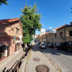 A street in Uzupis. The banner shows the "Republic" flag. A hand with a blue background.