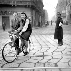 Un uomo e una donna, in sella a una "bici-coppia", a Milano, novembre 1947