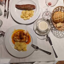 Top is pork with potatoes and Roquefort sauce on side, bottom is cod fish with potatoes