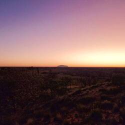 Die Sonne erwacht hinter Uluru...