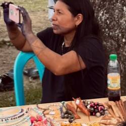 eine Embera-Indianerin bietet Schmuck feil und filmt nebenher den Tanzauftritt