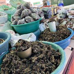 Street vendors selling dried wild spinach and bags of dried caterpillars