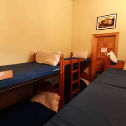 Bottom bunk in corner of crowded room