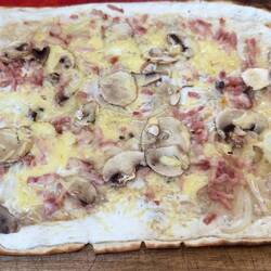 Tarte flambée is a thin, crispy flatbread topped with tart & cheese or bacon & onions.