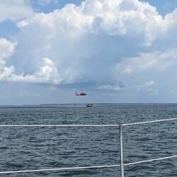Coast Guard practicing basket lifts from a boat, after dropping a diver to assist.