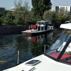 Ein Arbeitsboot fischt Müll aus dem Kanal