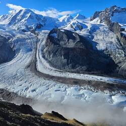 Different view of flowing glacier with cloud rising from below