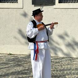 Igor, dressed in traditional garb, playing an instrument like a lute
