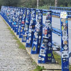 Bridge railing covered in stickers.