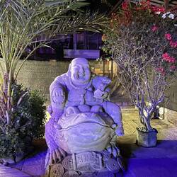 A hHappy buddha statue next to a restaurant on the beach front