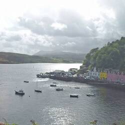 Bei der Rückkehr beleuchtet ein Sonnenstrahl die Bucht von Portree mit den markanten bunten Häusern