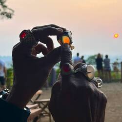 ein alter Dorfbewohner guckt die Sonne durch seine fetten Ringe an