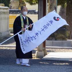 Ein Geistlicher spricht Besucher an, damit sie in seinen Tempel kommen.