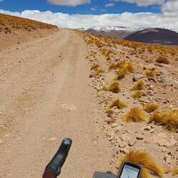 Cycling up higher and higher towards snow capped mountains