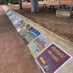 A mosaic wall in the town each one representing a local family or business