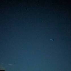 Starlink passing over the tops of the hills