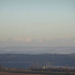 Im Kamerazoom sind schemenhaft die schneebedeckten Alpengipfel zu erkennen
