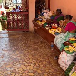 Ladies sewing necklaces of flowers for offerings.