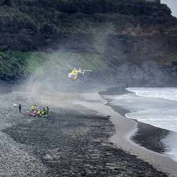 Der Hubschrauber wirbelt viel Sand auf. Wasser und Strand sind menschenleer.