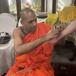 Friendly Monk putting prayer bands on our wrists.