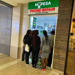 A group of locals in front of a small store managing MPESA