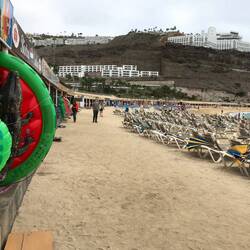 Playa de Amadores. Hufeisenstrand voll mit Geschäften und Gaststätten entlang des Strandes.