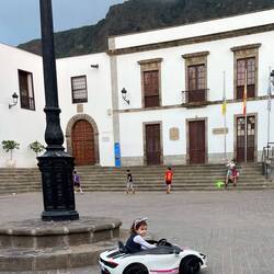 Das Mädchen im Sonntagsstaat dreht Runde um Runde - ganz stolz auf ihr Gefährt! Hintergrund: Rathaus