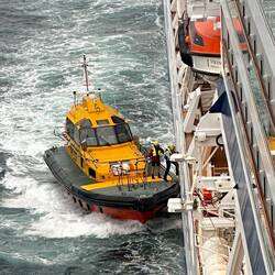The pilot jumps back on to the tug boat after guiding through the bay.