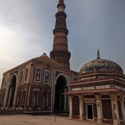 The domed building next to the Minar is the first mosque in India Quwwat-ul-Islam .