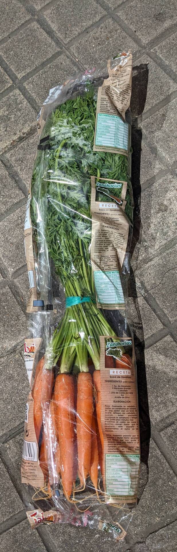 Carrots with long tops wrapped in plastic