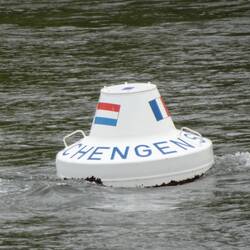 Het Drielandenpunt midden in de rivier, met de drie vlaggen erop draait hij heen en weer.
