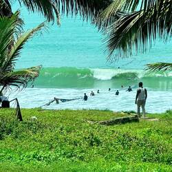 Men and boys duck as huge waves approach before continuing to work their fishing nets