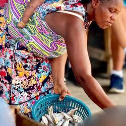 Her expression captures the effect of fish-smelling smoke and oil over intense heat below