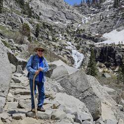 Charlie on the rocky, cliffside part of the trail. Note the long cascading waterfall and snow