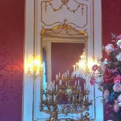 Incredible gold plated candlestick beneath a large gilded mirror
