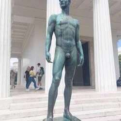 Bronze statue 'Young Athlete' by Josef Müllner in front of a reduced Greek copy of Theseus Temple