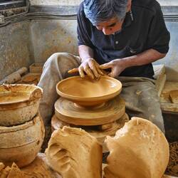 In 5 Minuten hat er eine wunderschöne Schale getöpfert. Er treibt d.Töpferscheibe mit d.Fuß an.