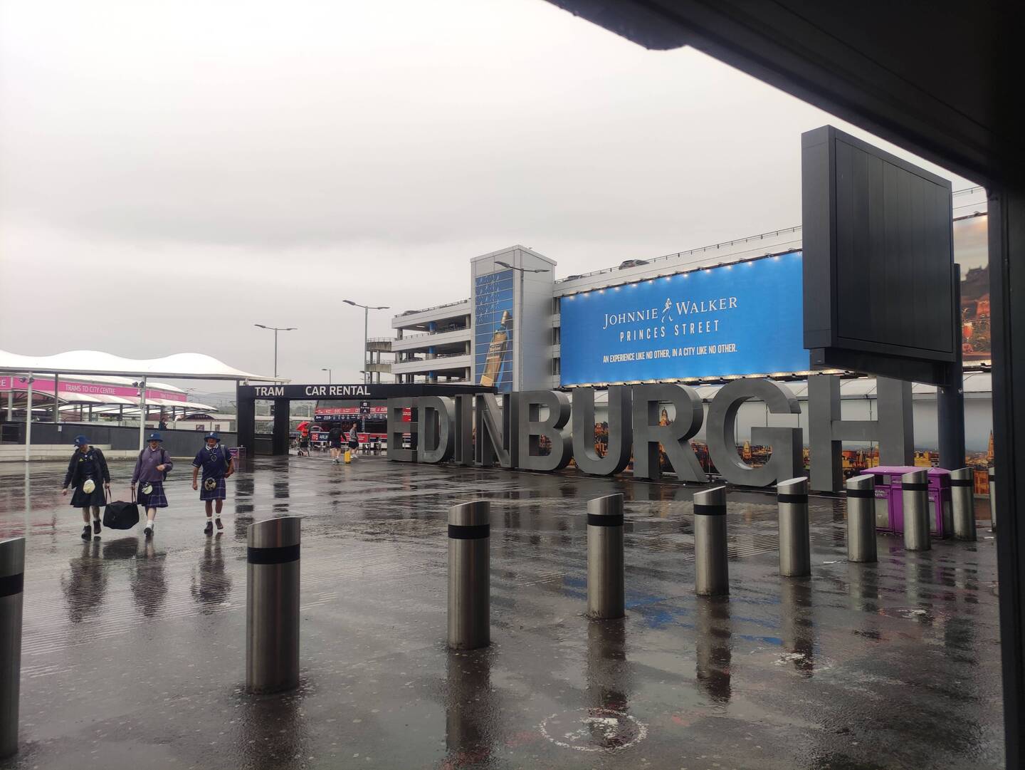 Schottischer kann die Ankunft nicht werden. Regen, Schotten in Kilt und Ein großes Edinburgh-Schild