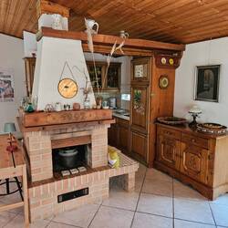 Zwischen Küche und Wohnraum ist ein großer Kamin.