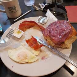 Breakfast: cinnamon Roll with blueberrysauce egg and bacon, and coffee